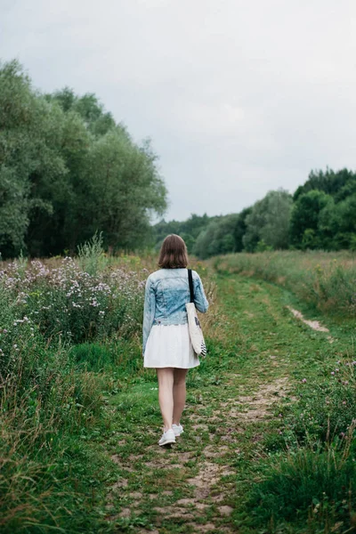 Πίσω όψη της νεαρής γυναίκας που περπατάει μόνη της στο χωράφι — Φωτογραφία Αρχείου
