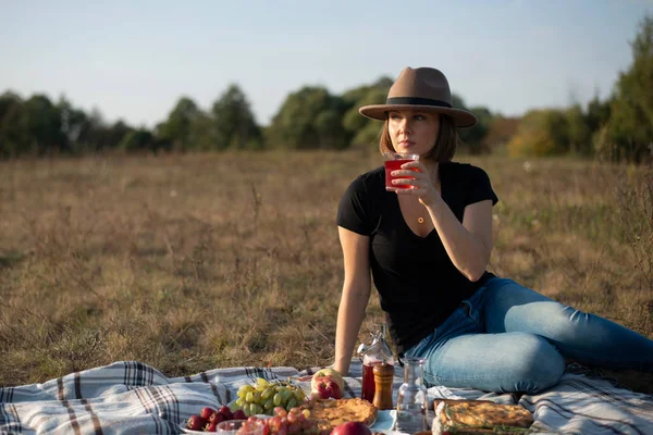 Pretty young woman enjoying picnic in sunny autumn field — Stock Photo, Image