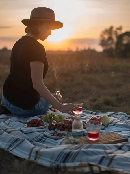 Pretty young woman enjoying picnic in autumn field at sunset — Stock Photo, Image