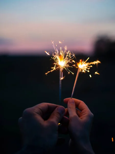 Hände, die in der Dämmerung funkelndes Feuerwerk in den Himmel halten — Stockfoto