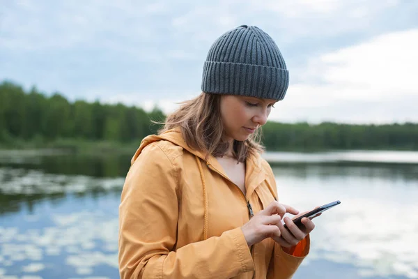 Woman Using Smartphone While Standing Lakeshore Cloudy Sky Royalty Free Stock Images