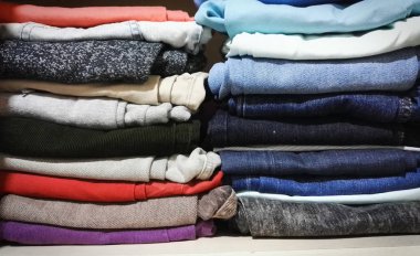 Pantolon (kot, joggers, davul) farklı parlak renklerde bir dolap raf üzerinde yığılmış
