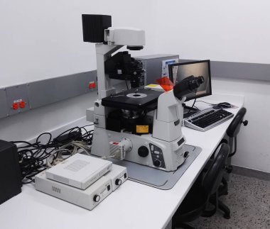 Resepsiyon ile bir yüksek teknoloji mikroskobu İstasyonu bilimsel bir laboratuvar. Yüksek büyütme floresans mikroskobu, bilgisayar, elektrik donanımları ve kabloları ters.
