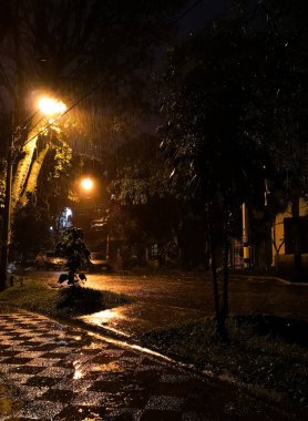 Soluk sarı ışık yansımaları ile ağır bir fırtına nedeniyle su ıslak karanlık yolda. Gizem sisli gece.