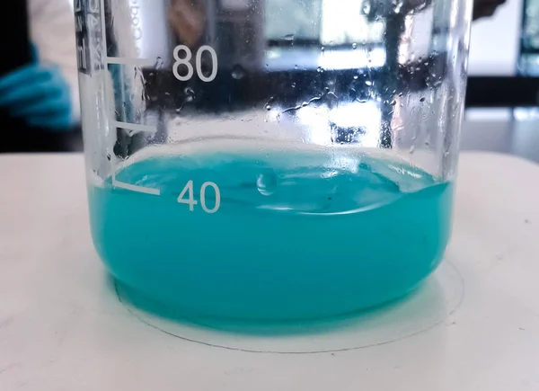 ガラス ビーカーの中にターコイズ ブルーやアクアマリン液体物質との化学反応 科学研究所背景 — ストック写真