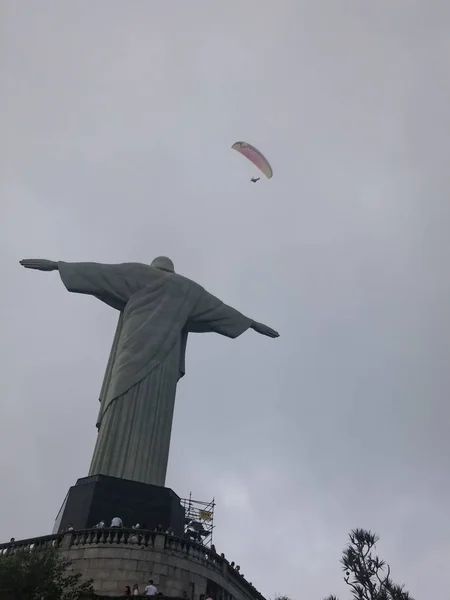 在它上空飞行的威严的救世主基督和滑翔伞的看法 旅游目的地和著名的地方在里约热内卢 宗教象征 — 图库照片