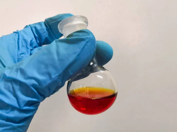 Ein Wissenschaftler Mit Schutzhandschuhen Hält Einen Glaskolben Mit Rötlicher Substanz — Stockfoto