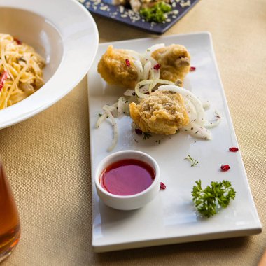 Tavuk halkası, nugget, siyah tabakta domates soslu kalamar.