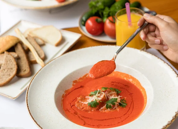 stock image Woman eating tomato soup with sauce on a black plate