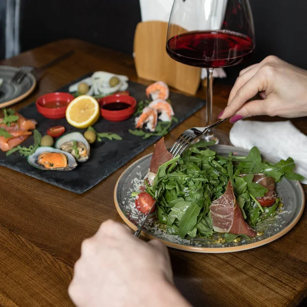 Two woman eating meat salad, snack with wine