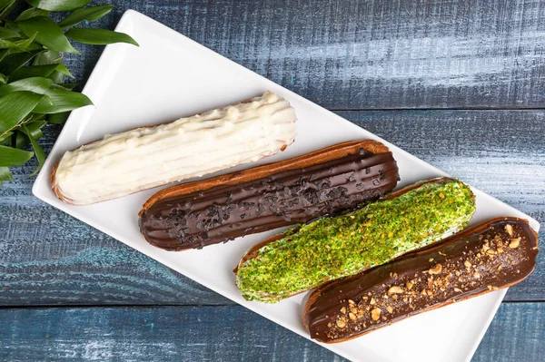 Savoureux Gâteaux Éclair Chocolat Avec Des Feuilles Sur Fond Bleu — Photo