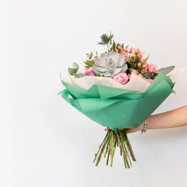 Beyaz arkaplanı olan renkli çiçek buketi tutan kadın.