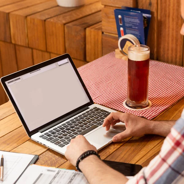 Man working on a laptop with dark beer drink