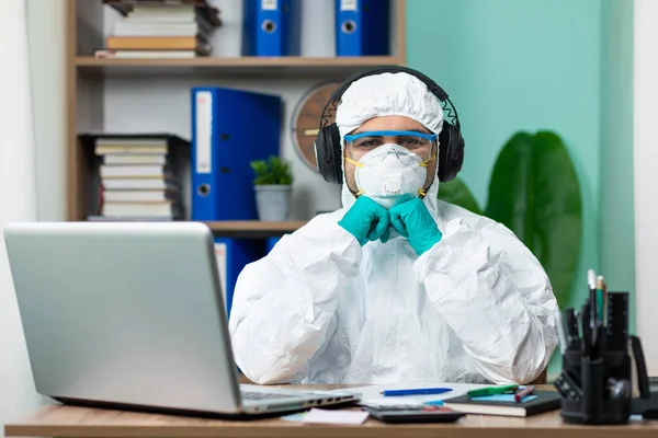 Disinfection man with special white suite listening music with headset at office