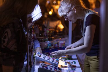 Kadın gece sergisinde aksesuar arıyor, alışveriş yapıyor.