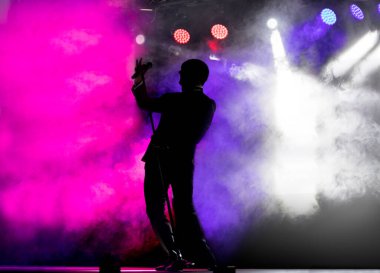 Şarkıcı silueti renkli sahnede şarkı söylüyor