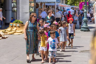 Çocuklar sergide öğretmenle yürüyor.