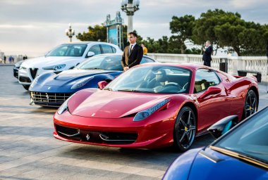 Kırmızı Ferrari diğer spor arabalarla sergide.
