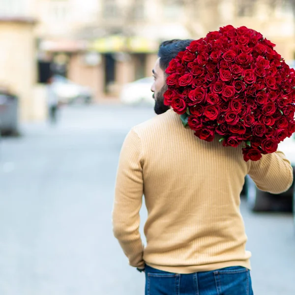 Kırmızı gül buketi tutan adam