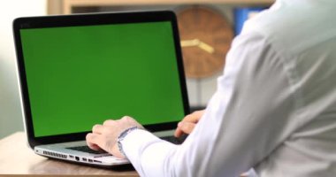 Yeşil ekranlı bir dizüstü bilgisayarda çalışan adam.