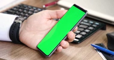 Ofis arka planında yeşil ekran akıllı telefon görüntüsü izleyen adam