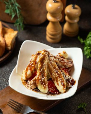 Lezzetli kızarmış patlıcan ve teriyaki soslu domates salatası ve susam tohumları, beyaz bir tabakta servis ediliyor, tadını çıkarmaya hazır.