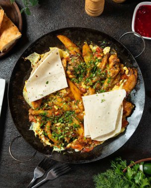 Cızırdayan tavuk ve patates tabağı büyük bir tavada pide ekmeği ve taze otlarla servis edilir. Lezzetli ve aromatik bir yemek.