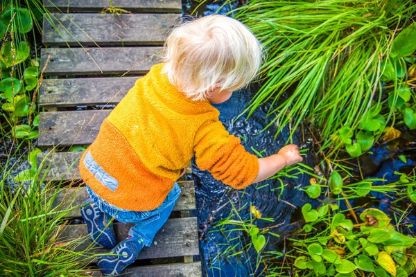 Biondo ragazzo giocare a piccolo ruscello in svedese natura — Foto Stock