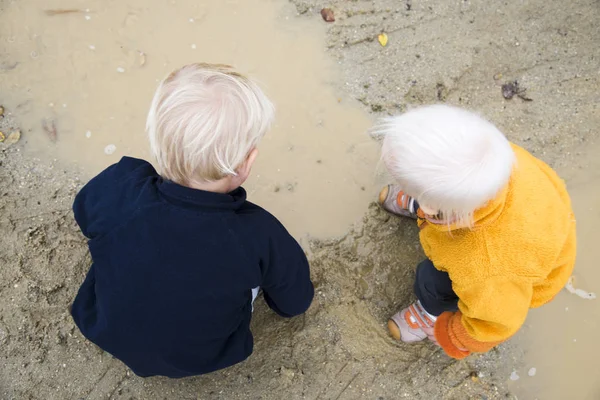 Due figli, fratelli, che giocano in una pozzanghera di fango — Foto Stock