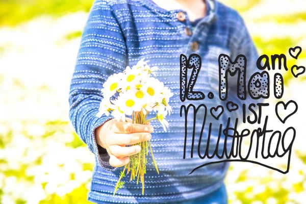 "Ребенок, букет ромашки", "Каллиграфия Муттертаг" означает "С Днем матери" — стоковое фото