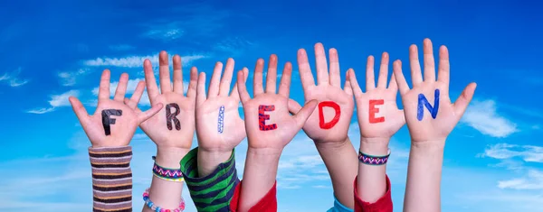 Kinderen handen bouwen woord Frieden betekent vrede, blauwe lucht — Stockfoto