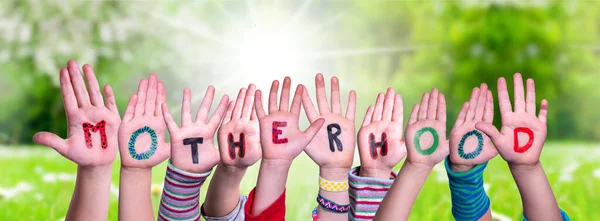 Niños Manos Construyendo Palabra Maternidad, Pradera de hierba — Foto de Stock