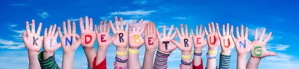 Kinderen handen vasthouden Woord Kinderbetreuung betekent kinderdagverblijf, Blue Sky — Stockfoto