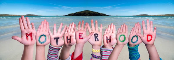 Kinderen handen bouwen Woord Moederschap, Ocean Achtergrond — Stockfoto