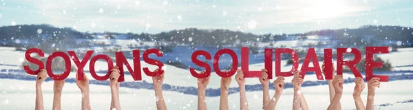 Άνθρωποι χέρια εκμετάλλευση Soyons Solidaire μέσα επίδειξη αλληλεγγύης, χιονισμένο φόντο — Φωτογραφία Αρχείου