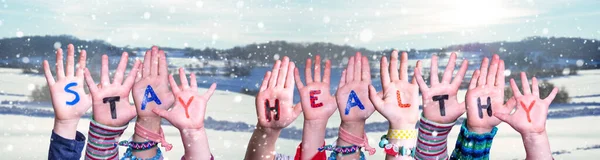 Crianças mãos segurando palavra Fique saudável, neve fundo de inverno — Fotografia de Stock