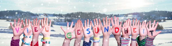 Dzieci ręce trzymając słowo Viel Gesundheit oznacza pobyt zdrowy, śnieg tle zima — Zdjęcie stockowe