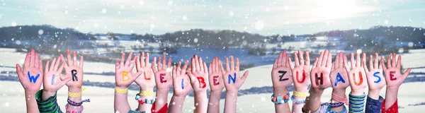 Le mani dei bambini che tengono Wir Bleiben Zuhause significano che restiamo a casa, sfondo invernale — Foto Stock