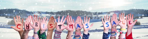 Barn händer byggnad Word jul försäljning, snöig vinter bakgrund — Stockfoto