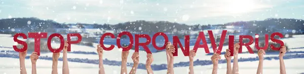 Manos de la gente sosteniendo la palabra Stop Coronavirus, fondo nevado del invierno — Foto de Stock