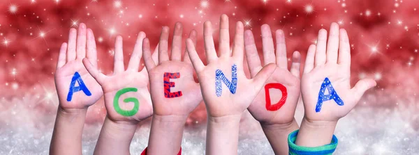Barn händer bygga Word Agenda, röd jul bakgrund — Stockfoto