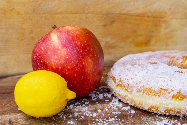 Red apple and lemon near to huge sugar doughnut, donut. Choice between healthy and bad food. Diet plan, longevity, nutrition choice.