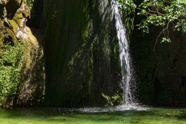 Dikey görüntü, ormanlardaki güzel şelale, temiz göl ve yosunlu kayalar. Ulusal ekoloji parkı. Yürüyüş, turistik yol.