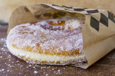 Lezzetli taze çörek ya da şeker kaplı çörekler ahşap masanın üzerinde duruyor..