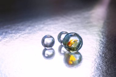 İki küçük ve bir büyük cam boncuk ya da gümüş arka plandan aydınlatılmış misket. Soyut grafik, tasarım ögesi, moleküllerin sembolü, su damlaları.