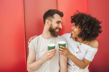 Tek kullanımlık kahve fincanı holding ve diğer her gülümseyen mutlu genç çok ırklı çift