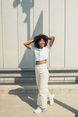 güzel mutlu genç Afro-Amerikan kadın sokakta başının arkasında elleri ile gülüyor