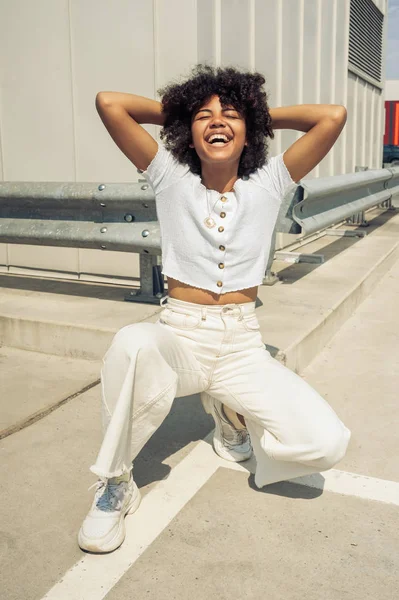 çömelmiş ve elle Caddesi üzerinde başının arkasında gülen mutlu Afro-Amerikan Kız