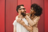 happy young interracial couple in eyeglasses hugging and smiling each other
