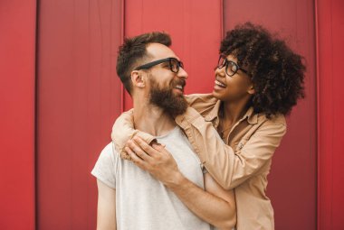 happy young interracial couple in eyeglasses hugging and smiling each other clipart